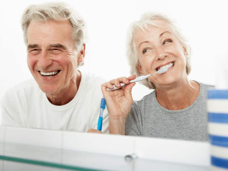 Pareja cepillándose los dientes, higiene diaria de las encías
